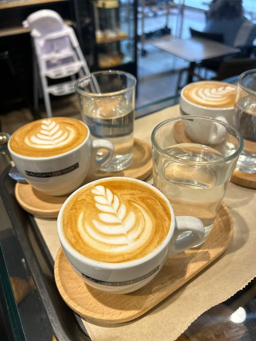 Dos cafés con leche con arte latte sobre bandejas de madera
