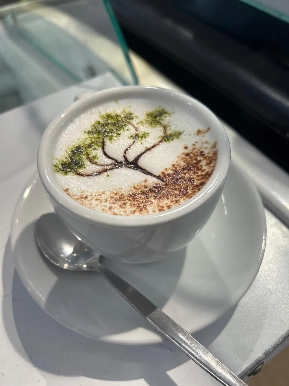 Capuchino con un árbol dibujado en la espuma con cacao y matcha