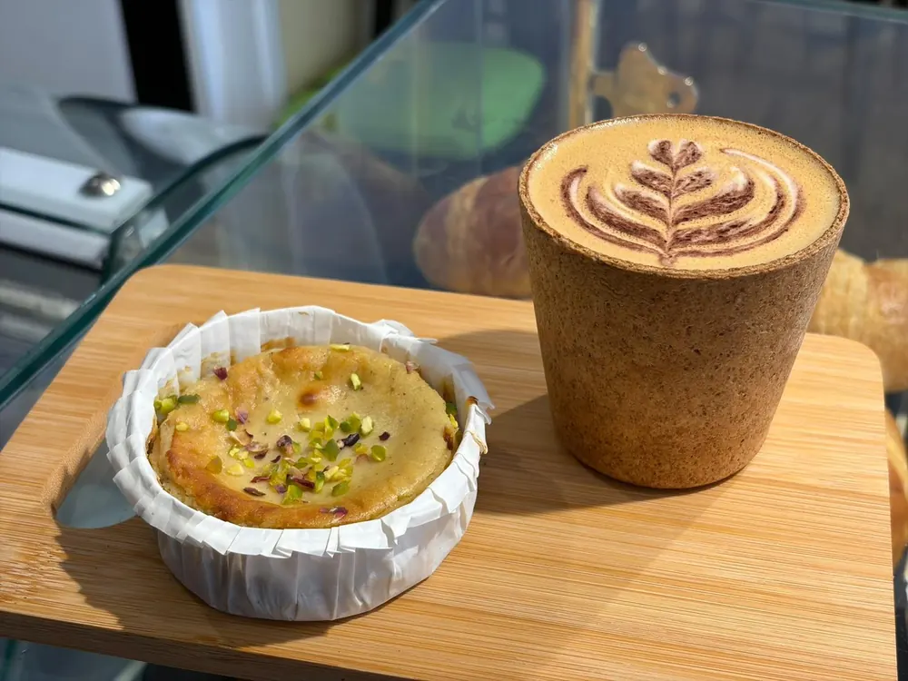 Bizcocho de pistacho y café con arte latte en vaso de corcho