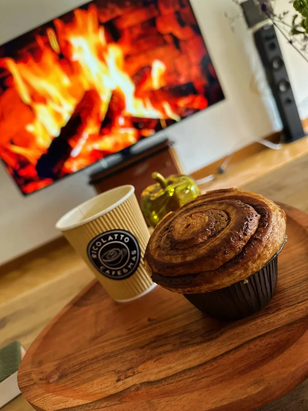 Napolitana de hojaldre en espiral junto a un vaso de café para llevar de Ricolatto